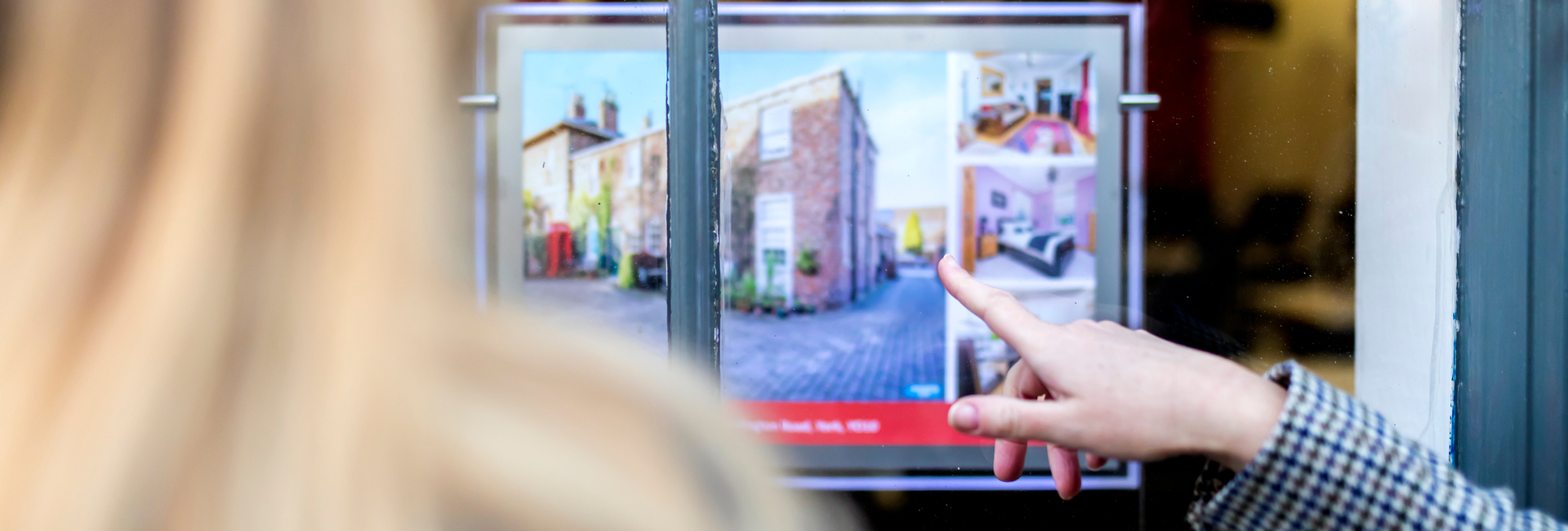 Two people look at a house for sale advert in an estate agent’s window